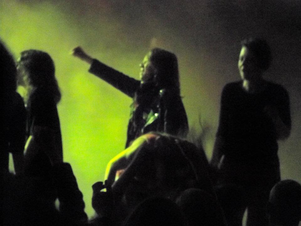 scena z koncertu muzyki rockowej, wśród tłumu słuchaczy wyróżnia się dziewczyna z wyciągniętą ręką